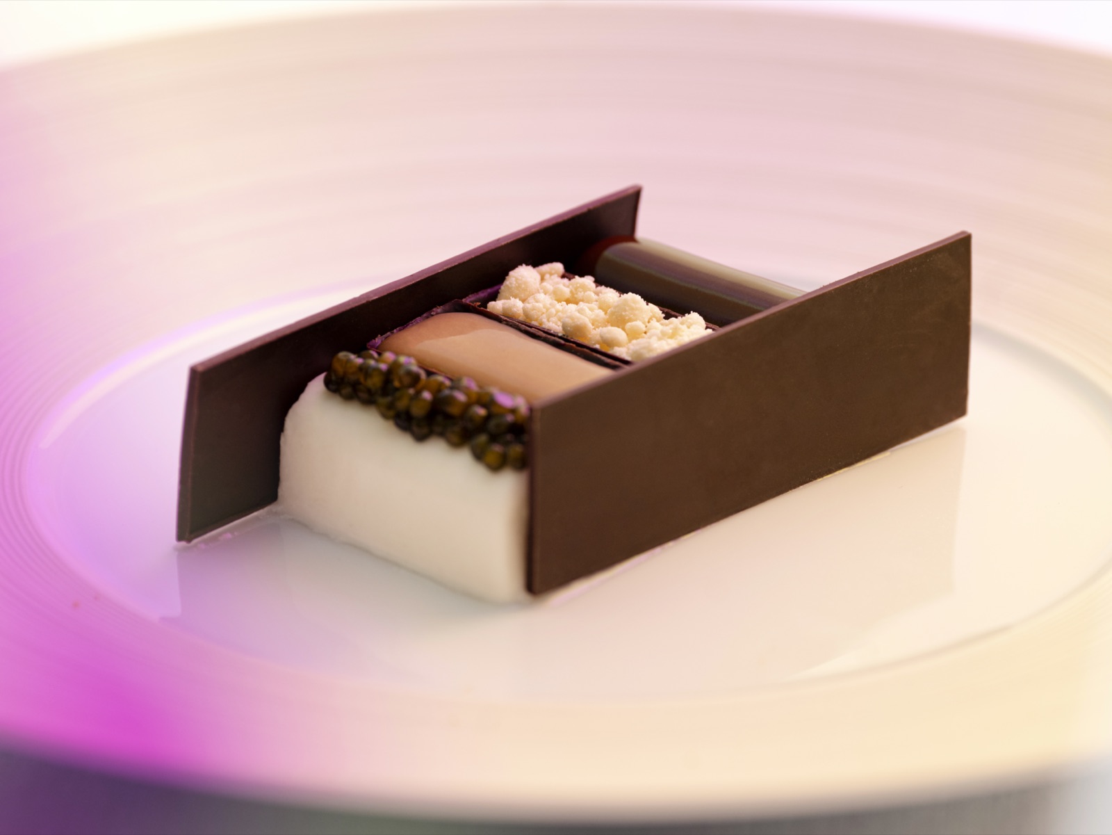 LUMIÈRES JéJé dessert — chocolate construction on pink-lit plate, art cuisine