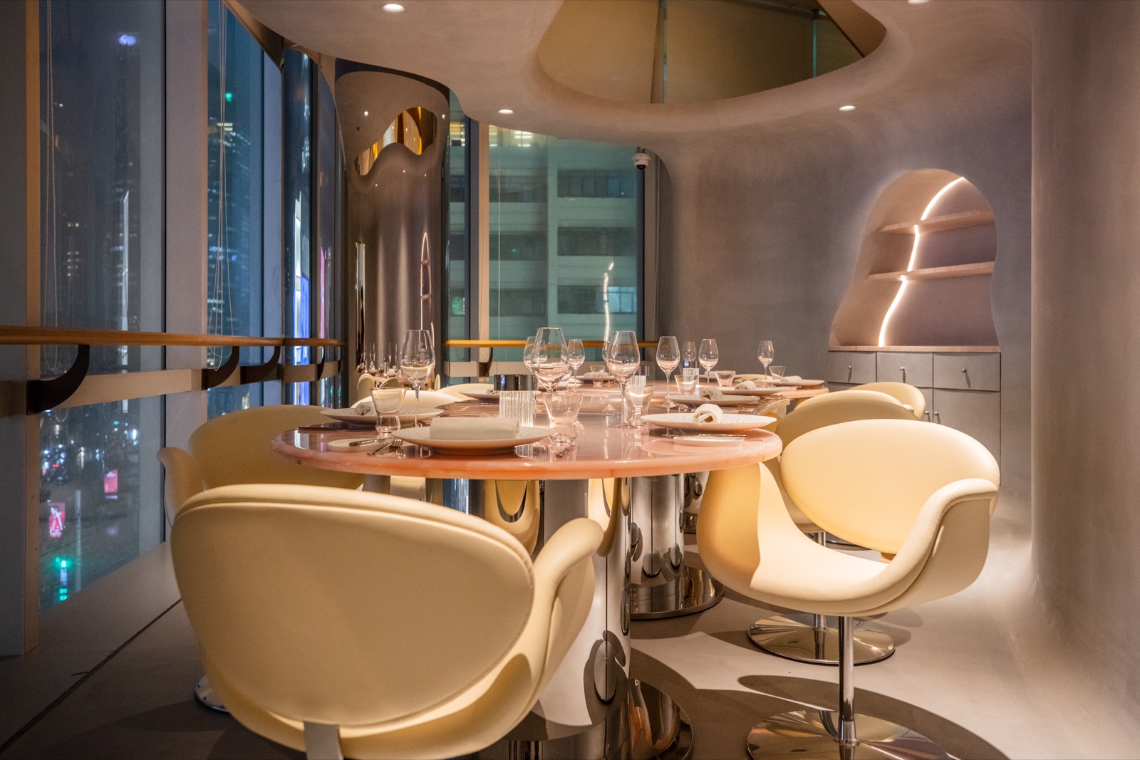 LUMIÈRES JéJé restaurant interior — pink marble table, warm evening light, elegant dining room