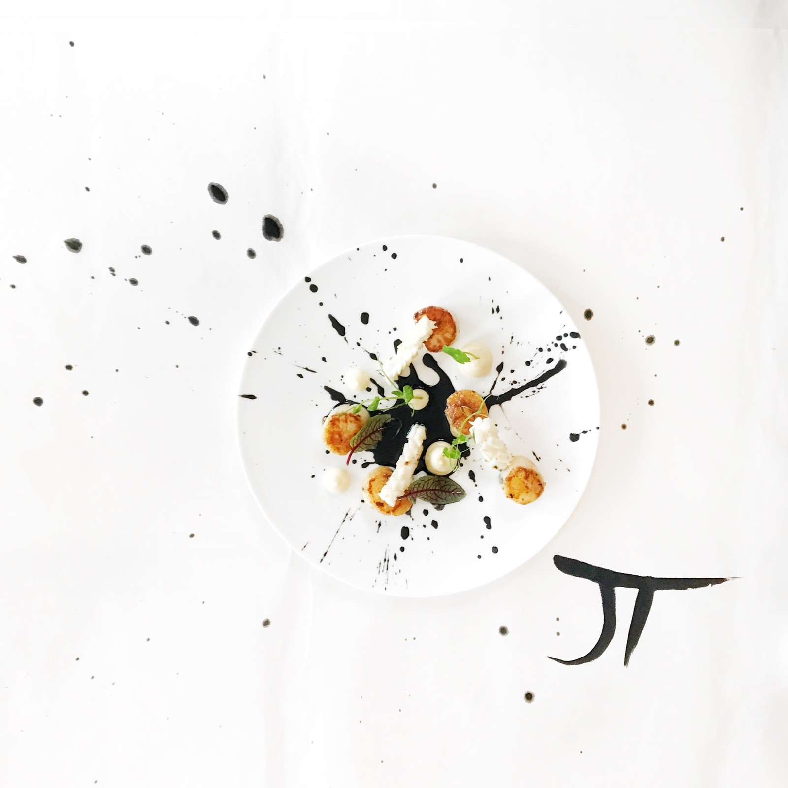 Scallops with black ink splatter — art cuisine by Jérôme Tauvron, signed JT